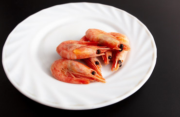 Red shrimp in a white plate on a black