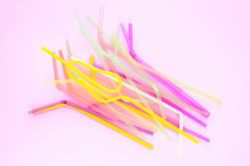 Colorful plastic drinking straws on a pink background. Top view.
