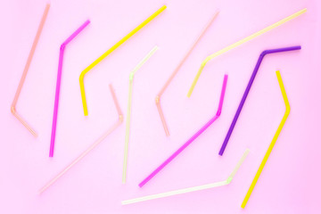 Colorful plastic drinking straws on a pink background. Top view.