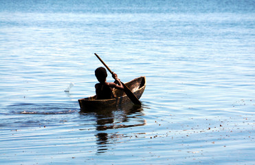 Fototapeta na wymiar little boy in canoe in auki island - biak island in indonesia