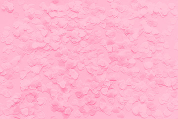 Festive romantic gentle abstract background for the design. Pink confetti in the shape of hearts on pastel background. Top view, flat lay composition. Copy space for text.
