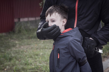The man put his hand over the child's mouth to stop the boy from screaming.