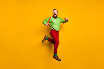 Fototapeta na wymiar Full length photo of careless childish crazy funky man jump pull his modern suspenders scream feel rejoice wear stylish outfit shoes isolated over yellow color background