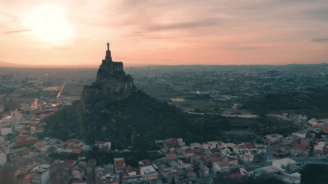 Aerial footage circling the Sacred heart statue of Jesus on top of Monteagudo castle near Murcia Spain during sunset