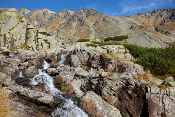 Beautiful landscape of a cascade mountain stream with peaks in the background at Skok waterfall in High Tatras National Park, Slovakia © andras_csontos