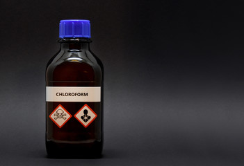 Chloroform in brown laboratory bottle stock images. A bottle of chloroform with inscription. Brown lab bottle. Brown glass container. Phial with warning pictograms on a black background
