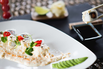 Traditional rolls with fish and rice on a white plate with sauce and wasabi. Japanese food.