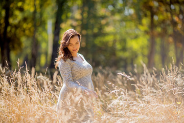 young pregnant brunette woman in grey knitted dress, pregnant girl in spring on a walk, maternity concept