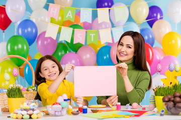 Portrait of nice attractive lovely creative cheerful cheery girls holding in hands blank paper creating handicraft April day bright vivid shine vibrant blue color background