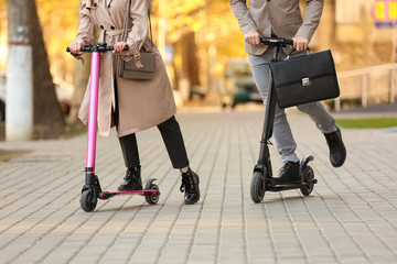 Young couple riding kick scooters outdoors
