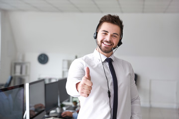 Portrait of male technical support agent showing thumb-up in office