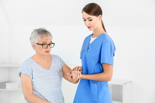 Female doctor with senior woman suffering from Parkinson syndrome in clinic