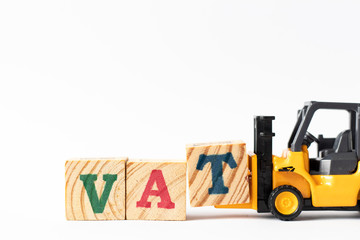 Toy forklift hold wood letter block T to complete word VAT (Abberviation of Value added tax) on...