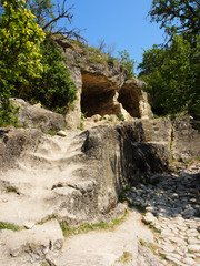 Cave city in the mountains, the entrance to the cave with a stone staircase in the foreground.