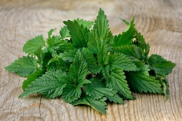 Fresh nettle leaves in a bowl on wooden background close up