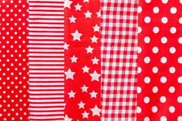Vertical textural background of five types of red and white cotton fabric with different prints: checkered, striped, circle, star. Selective focus. Closeup view