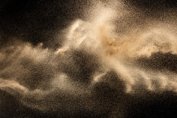 Naklejka na ściany i meble Brown colored sand splash.Dry river sand explosion isolated on black background. Abstract sand cloud.