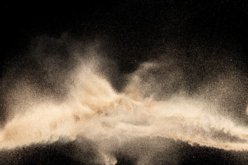 Brown colored sand splash.Dry river sand explosion isolated on black background. Abstract sand...