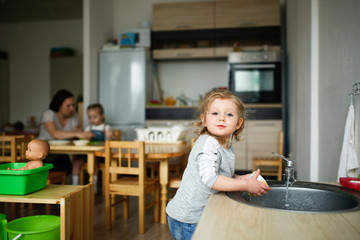 baby washes dishes in sink montessori center