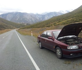 Fototapeta na wymiar Car breakdown on the side of the empty road, mountains in the background