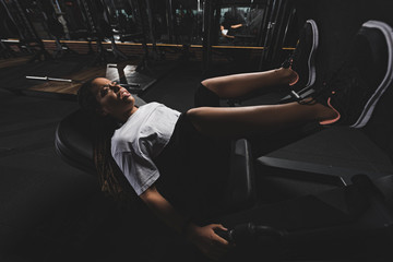 emotional african american sportswoman working out on fitness machine