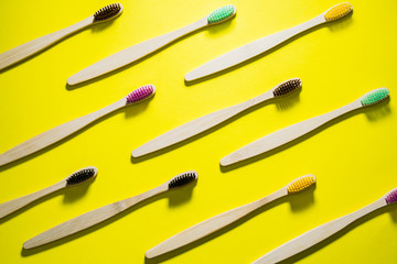 Eco bamboo toothbrashes with multicolored bright bristles on yellow background