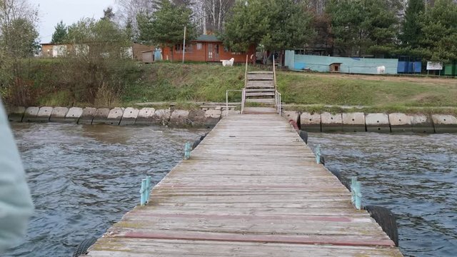 Girl runs towards runs backon old wooden pier. Autumn landscape is on background. Eye angle view.