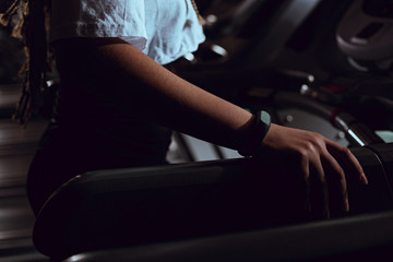 Plakat Cropped view of african american woman holding treadmill by hand with smart watch
