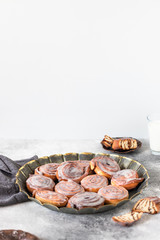 Cinnamon rolls or cinnabon with white cream glaze on a vintage plate. Cinnabons served on a gray table. Traditional homemade sweet buns. Selective focus, light tones, copy-space