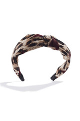 Subject shot of a fabric headband with a knot and beige and brown leopard print. The hair holder is isolated on the white background with shadows.