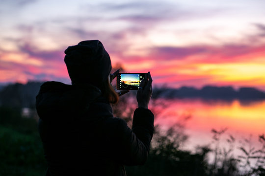 horizontal photo of a girl with a phone on the background of a beautiful sunset
