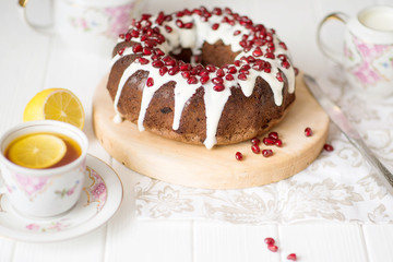 Chocolate Simnel Cake, muffin round hole (pie, cake) with white icing and pomegranate on a white table. English dish for the holiday, English tea party