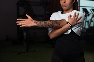 cropped view of tattooed african american woman exercising in gym