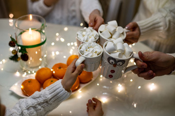 horizontal closeup photo of hands doing clink of cups with marshmallows