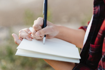 Hand of young girl writing on note book with pen.