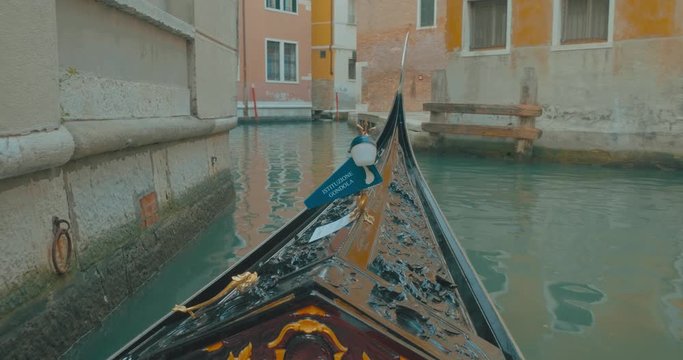 POV shot of traditional gondola slowly sailing past venetian restaurants