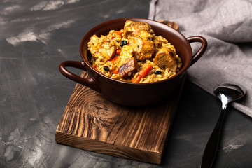 Large portion of pilaf in a clay dish. Delicious uzbek homemade meal