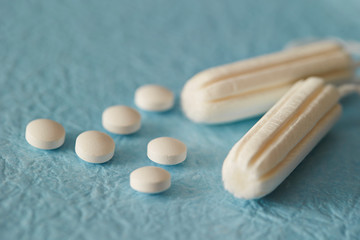 Pills and tampon on blue background 