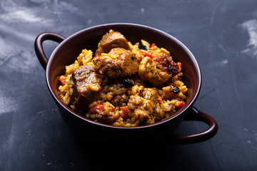 Large portion of pilaf in a clay dish. Delicious uzbek homemade meal. Toned