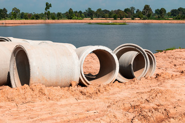 Large cement pipes on the ground to wait for installation under the soil. Riverside in the countryside of Thailand.