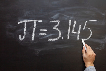 Hand writing the number Pi on a chalkboard