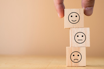 Hand select and putting smile cube emotion for stacking to normal and sad emotion wooden...