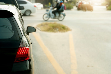 Car stop on junction road and open brake light. with other cars and motorcycle pass to the front.