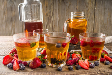 Sweet homemade fermented Kombucha drink. Kombucha fruit and berry tea, on wooden background with fresh berries