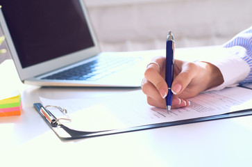 Businesswoman sitting at office desk signing a contract or making notes.