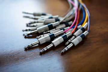 Close up of a bunch of audio jack plugs with colourful cables, selective focus and narrow depth of field