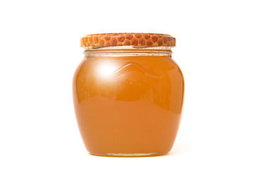 Glass jar with fresh bright honey on a white wall background. The concept of healthy eating and healthy foods.