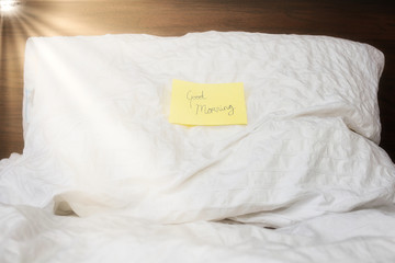 Little yellow not on pillow on bed with 
