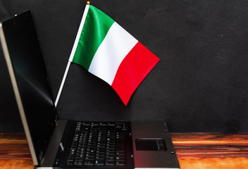  flag of Italy,  computer, laptop  on table and dark background