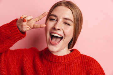 Photo of joyful beautiful woman gesturing peace sign and winking